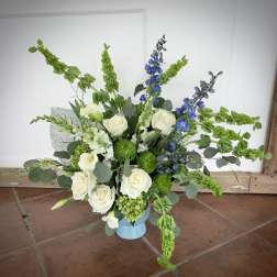 White roses and blue delphinium in a light blue vase