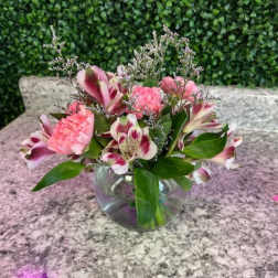 Pink and white flowers arranged in a clear glass bowl vase