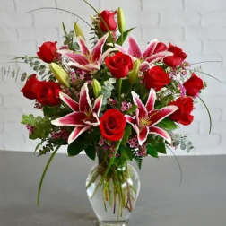 Red roses and pink lilies arranged in a clear glass vase