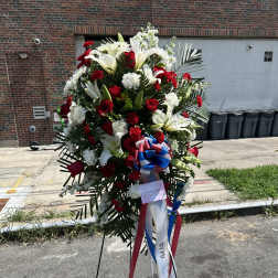 Standing floral spray with red roses, white lilies, and ribbon streamers