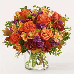 Orange roses and purple mums in a clear glass vase
