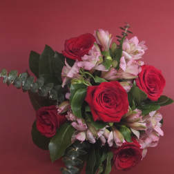 Bouquet of red roses and pale pink alstroemeria on a pink background