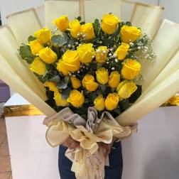 Bouquet of yellow roses wrapped in cream paper with a ribbon