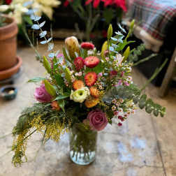Mixed bouquet of pink, orange, and white flowers in a glass vase