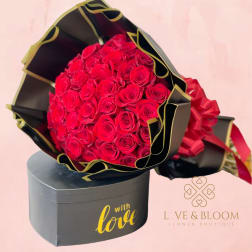 Bouquet of red roses in black and gold wrapping with a gift box