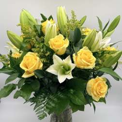 Yellow roses and white lilies in a glass vase