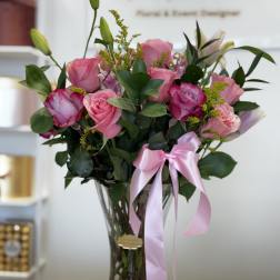 Pink roses in a clear glass vase with a pink ribbon