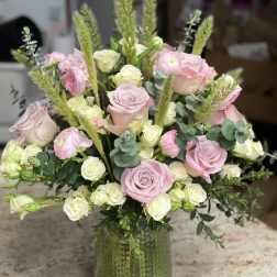 Pink and white roses arranged in a green glass vase