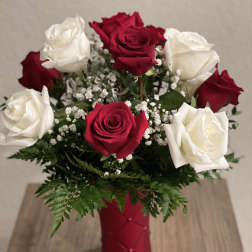 Red and white roses in a red vase with baby's breath