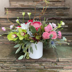 Pink roses and orchids arranged in a white textured vase