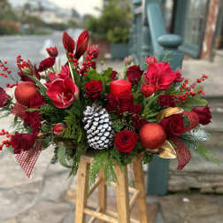 Red floral arrangement with pinecone and ornaments in a container