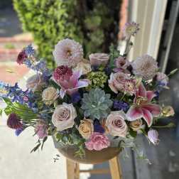 Mixed pastel bouquet with roses, lilies, and dahlias in a low container