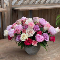 Mixed pink and white roses arranged in a gray vase