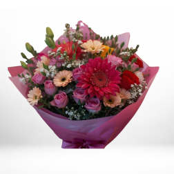 Bouquet of pink, red, and peach flowers wrapped in magenta paper