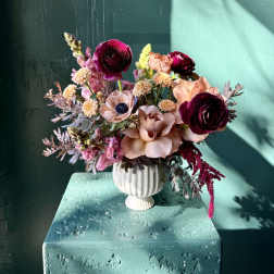 Mixed pink and peach flowers arranged in a white vase