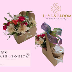 Kraft caddy holding pink and cream flowers beside an iced coffee cup with a multicolor ribbon bow.