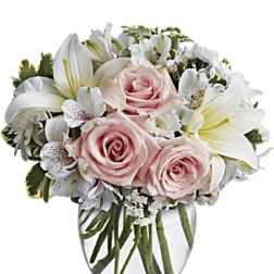 Pink roses and white lilies arranged in a clear glass vase