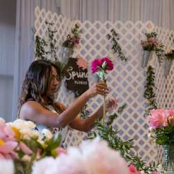 Woman arranging a pink flower on a lattice floral display