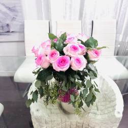 Pink roses arranged in a vase with trailing greenery