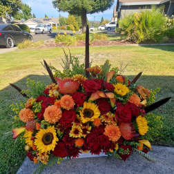 Large arrangement of red, orange, and yellow flowers in a low container
