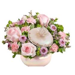 Pink roses and small purple flowers arranged in a round box with a lid