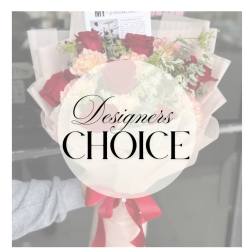 Bouquet of red and blush roses wrapped in pale paper with a pink ribbon