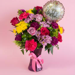 Mixed bouquet in a purple vase with a birthday balloon