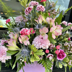 Pink and lavender mixed flower arrangement in a lavender container