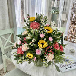 Mixed bouquet with sunflowers, pink carnations, and white daisies in a glass vase