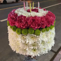 Round floral cake with pink, white, and green flowers and striped candles