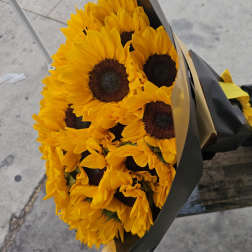 Bouquet of yellow sunflowers wrapped in black paper with a yellow ribbon