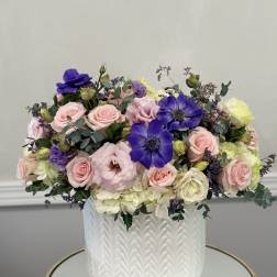 Mixed pink and purple flowers arranged in a white textured vase