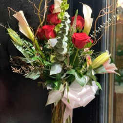 Bouquet of red roses and white lilies with greenery and a pale ribbon