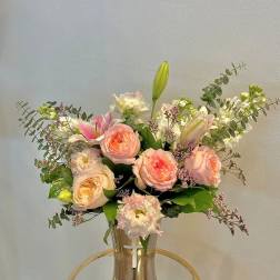 Pink roses and lilies arranged in a clear vase