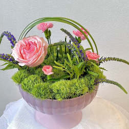 Pink roses and carnations arranged in a pink pedestal bowl