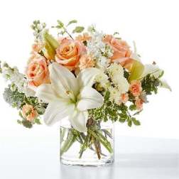 Peach roses and white lilies in a clear glass vase