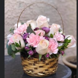 Basket of pink and white roses with purple carnations