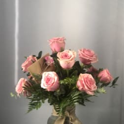 Pink roses arranged in a glass vase with a burlap ribbon