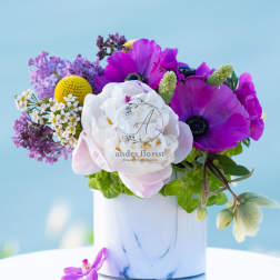 Purple and white flowers arranged in a white vase
