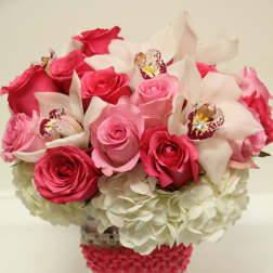 Pink roses and white orchids in a clear square vase