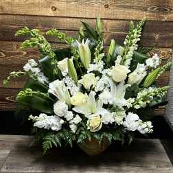 White lilies and roses arranged in a low urn with greenery
