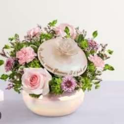 Pink roses and purple flowers arranged around a decorative hat box