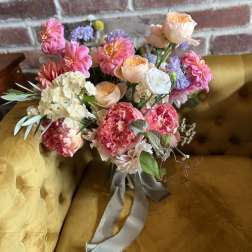Bouquet of pink, peach, and white flowers tied with a gray ribbon