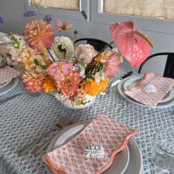 Pastel floral centerpiece with pink anthurium, dahlias, and roses on a set table