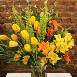 Mixed bouquet of yellow and orange flowers in a clear glass vase