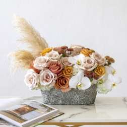 Mixed roses and white orchids in a gray container