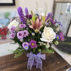 Bouquet of pink lilies, white roses, and purple daisies in a vase