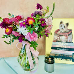 Mixed pink and purple bouquet in a glass vase with a ribbon
