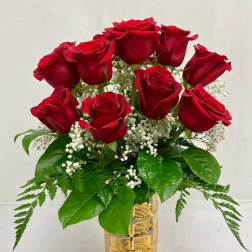 Red roses arranged in a gold vase with baby's breath