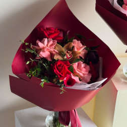 Bouquet of red and pink flowers wrapped in burgundy paper